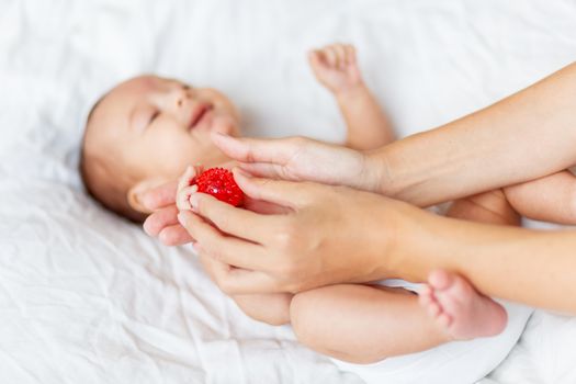 Mother holds newborn baby's palm hands. Tiny fingers in woman's hand. Cozy morning at home.