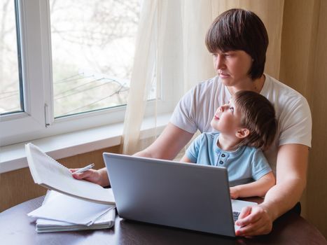 Self-isolation because of coronavirus outbreak. Man is remote working with his little son on self quarantine. Lockdown.