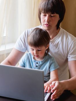 Self-isolation because of coronavirus outbreak. Man is remote working with his little son on self quarantine. Lockdown.