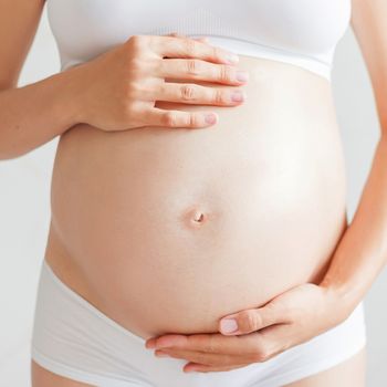 Pregnant woman in white underwear. Young woman expecting a baby.