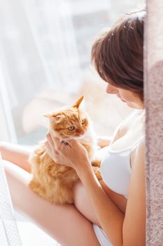 Pregnant woman in white underwear with cute ginger cat. Young woman expecting a baby. Risk of infection toxoplasmosis.