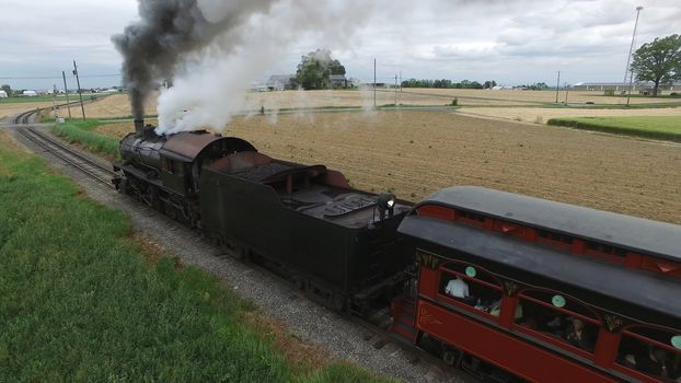 Aerial View of a Steam Passenger Train Puffing Smoke in Amish Countryside on a Sunny Spring Day