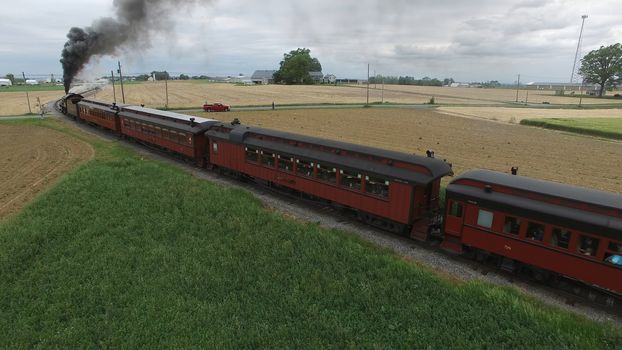 Aerial View of a Steam Passenger Train Puffing Smoke in Amish Countryside on a Sunny Spring Day