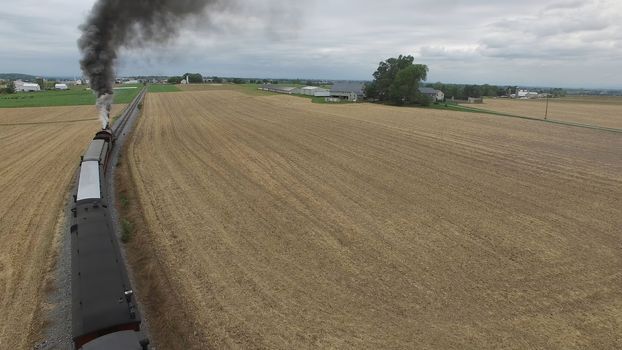 Aerial View of a Steam Passenger Train Puffing Smoke in Amish Countryside on a Sunny Spring Day