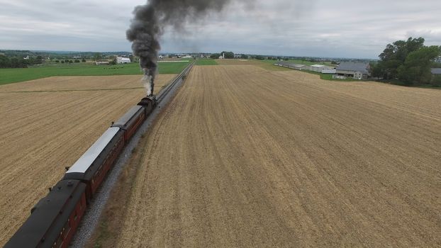 Aerial View of a Steam Passenger Train Puffing Smoke in Amish Countryside on a Sunny Spring Day