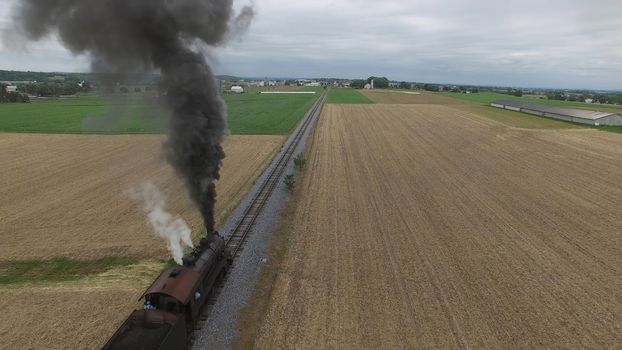 Aerial View of a Steam Passenger Train Puffing Smoke in Amish Countryside on a Sunny Spring Day