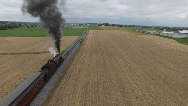 Aerial View of a Steam Passenger Train Puffing Smoke in Amish Countryside on a Sunny Spring Day