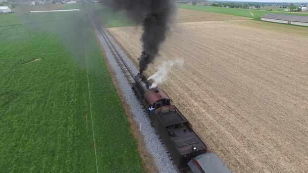 Aerial View of a Steam Passenger Train Puffing Smoke in Amish Countryside on a Sunny Spring Day