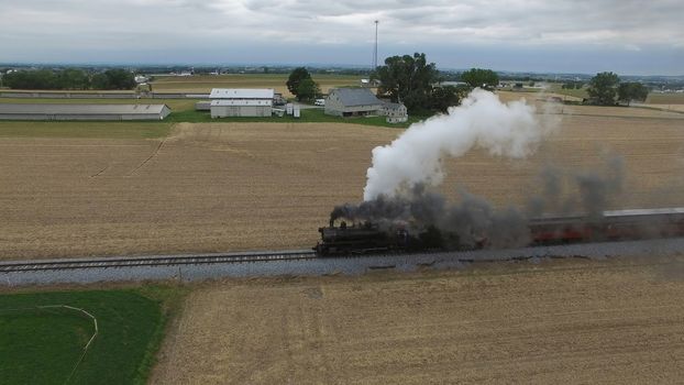 Aerial View of a Steam Passenger Train Puffing Smoke in Amish Countryside on a Sunny Spring Day