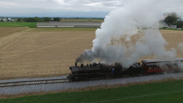 Aerial View of a Steam Passenger Train Puffing Smoke in Amish Countryside on a Sunny Spring Day