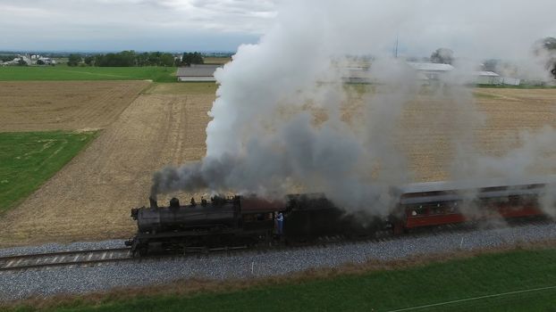 Aerial View of a Steam Passenger Train Puffing Smoke in Amish Countryside on a Sunny Spring Day