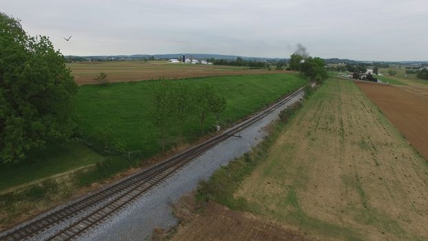 Aerial View of a Steam Passenger Train Puffing Smoke in Amish Countryside on a Sunny Spring Day