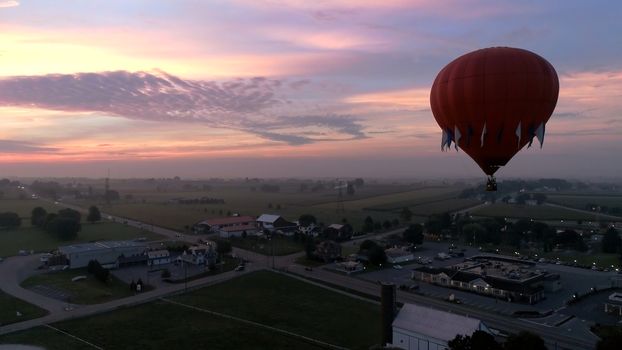 Aerial View of Sunrise with Hot air Balloons Taking Off with Glow as Seen by a Drone