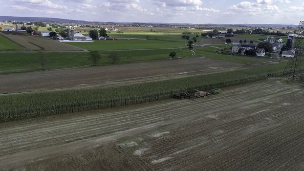 Aerial View of Amish Farmers Harvesting Their Crops on an Autumn Day with Teams of Horses as Seen by a Drone