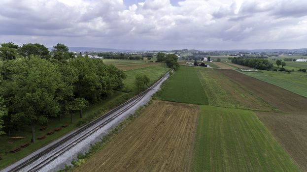 Aerial View of a Steam Passenger Train Puffing Smoke in Amish Countryside on a Sunny Spring Day