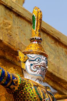 Sculpture in Royal Palace, Bangkok, Thailand. Wat Phra Keo. Architecture detail - face of mythical creature in golden hat.