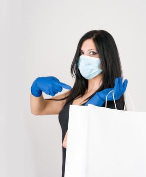 beautiful woman recommends what to wear for prevention, gloves and mask with shopping bag. isolated