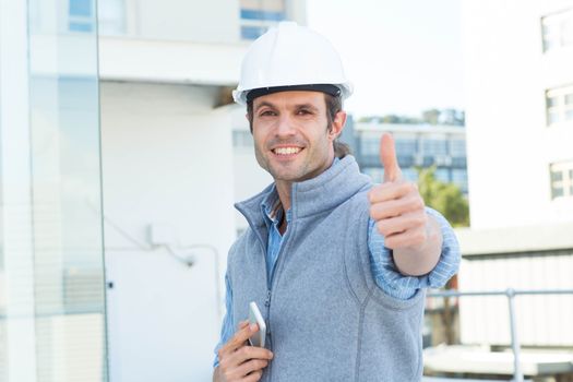 Portrait of handsome male architect gesturing thumbs up outdoors