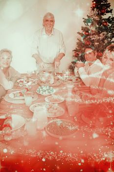 Happy grandfather carving the christmas turkey against glittering christmas tree design