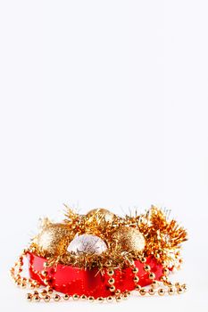 Golden and silver balls in box with tinsel and beads. Christmas and New Year decorations in red box on white background. Copy space.