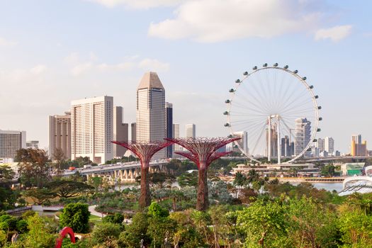 Singapore, panorama view - big wheel, hotel's buildings, Gandens at the Bay, road and bridge at sunset.