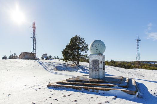 Meteorological tower and monument on the top of Ai-Petri mountain. Snow and frosted pine trees in sunny day. Crimea, Russia.
