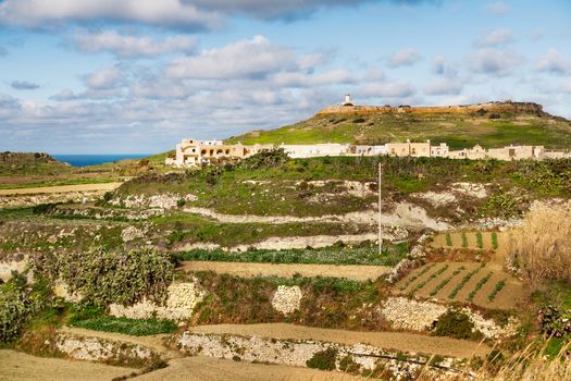 Panoram view on fields and lighthouse on the top of mountain. Gozo island, Malta.