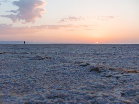 Sunrise in Sahara desert. Two man greeted dawn at salt lake. Egypt.