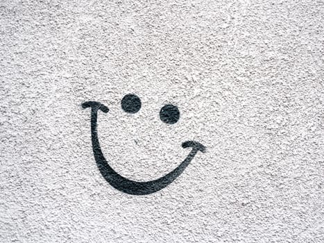 Smiling face on concrete surface. Eyes and lips drawn on outdoor wall.