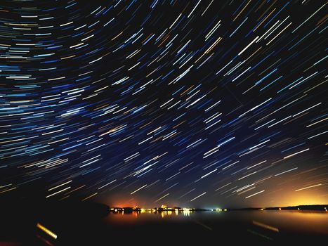 Gorgeous star tracks over Seliger lake in Ostashkovsky District of Tver Oblast. Long exposure of starry night sky. Russia.