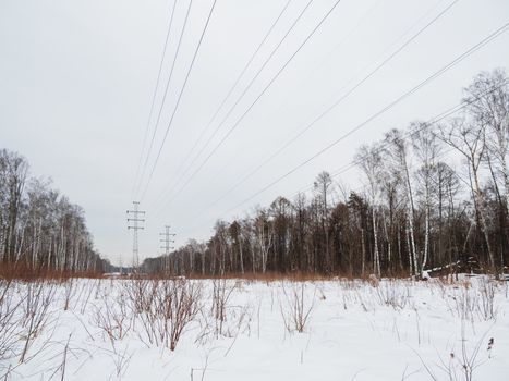 Power line towers in Losiny Ostrov National Park. Elk Moose Island in Moscow, Russia. Winter or early spring landscape.