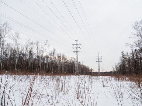 Power line towers in Losiny Ostrov National Park. Elk Moose Island in Moscow, Russia. Winter or early spring landscape.