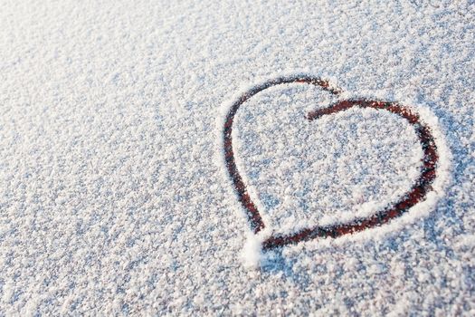 Heart drawn in snow. Symbol of love. Winter sunny day.