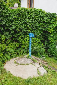 Metal sewerage hatchway and old fashioned water standpipe with bas relief. Iron manhole. Serpukhov, Russia.