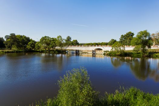 Old bridge in Bolshie Vyazyomy Manor, Moscow region, Russia. Natural landscape background with lake, forest and bridge.