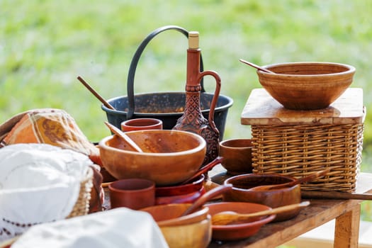 Wooden table with old fashioned wooden and earthenware crockery. Historical reconstruction of 19 century.