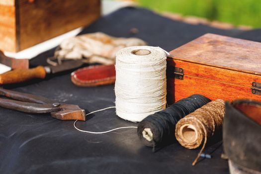 Old fashioned shoemaker set - shoes, spools of thread, tools, workpieces. Historical reconstruction of 19 centure.