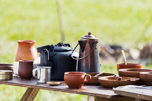 Wooden table with old fashioned wooden and earthenware crockery. Historical reconstruction of 19 century.