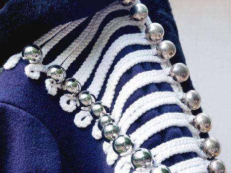 Shiny metal buttons on deep blue hussar's jacket. Old fashioned military uniform on annual festival Times and Epochs. Historical reconstruction. Moscow, Russia.