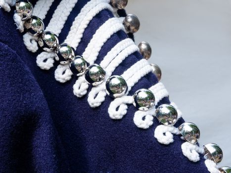 Shiny metal buttons on deep blue hussar's jacket. Old fashioned military uniform on annual festival Times and Epochs. Historical reconstruction. Moscow, Russia.