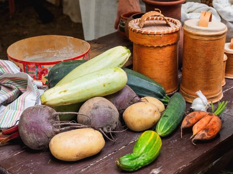 Fresh vegetables and vintage dinnerware, birchbark crockery and old fashioned household items on historical festival Times and Epochs. Moscow, Russia.