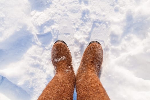 Russian traditional winter footwear - valenki. Winter sunny day, top view on feet felted wool boots.