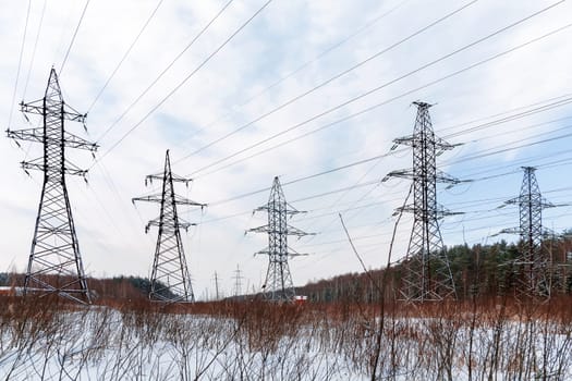 Power line in a winter forest. Electric equipment stays in snowy field. Russia.