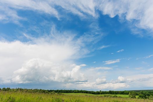 Countryside natural background. Rural path winds along the field. Cloudscape in sunny day. Russia.