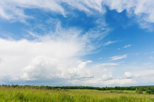 Countryside natural background. Rural path winds along the field. Cloudscape in sunny day. Russia.