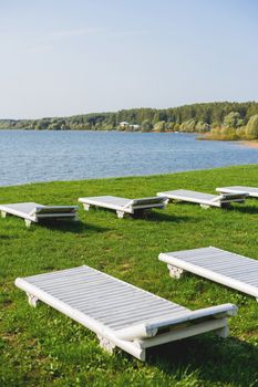 White wooden chaise lounges on the bank of the Ilyinsky reservoir. Outdoor recreation. Moscow region, Russia.