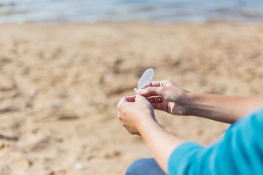 Woman holds a white feather of a seagull in hand. Symbol of lightness and fragility.