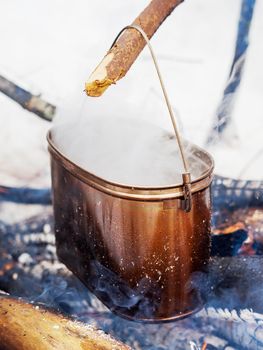 Cooking soup on a fire pot. Winter camping in forest.