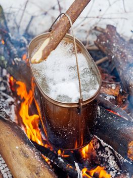 Cooking soup on a fire pot. Winter camping in forest.