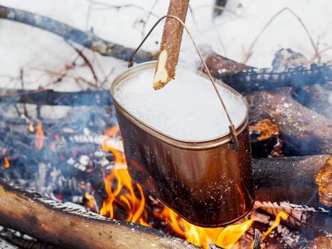 Cooking soup on a fire pot. Winter camping in forest.